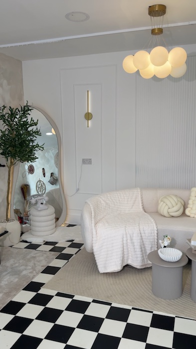 A short pan across the arched mirror, potted tree, checkerboard floor and cream sofa lounge.